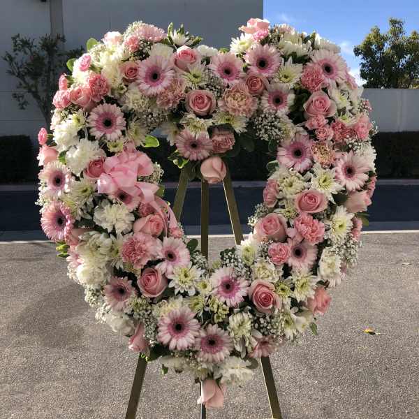 Heart-shaped floral wreath on an easel with pink and white flowers