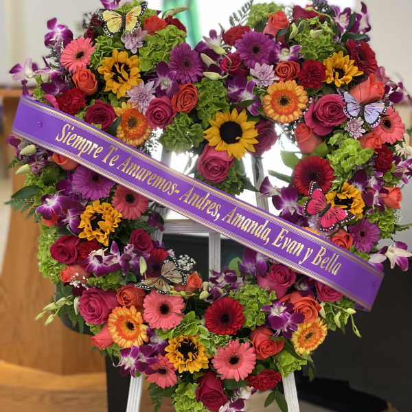 Heart-shaped floral wreath on an easel with a purple memorial ribbon