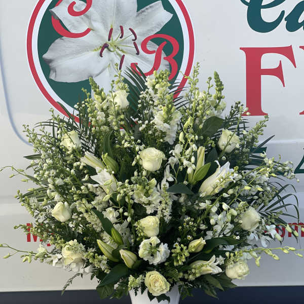 Large white floral arrangement in a white urn vase