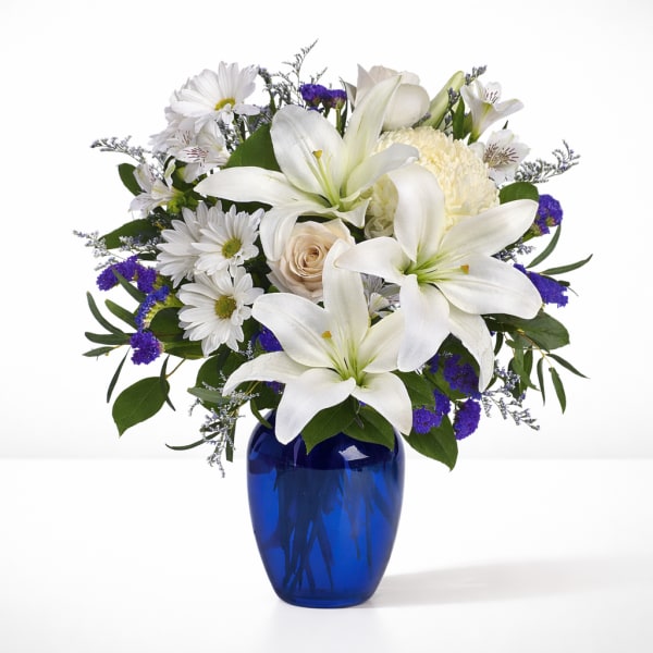 White lilies and daisies in a blue glass vase