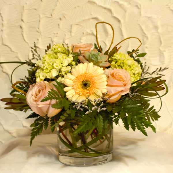 Bouquet of pale pink roses and a peach gerbera daisy in a glass vase