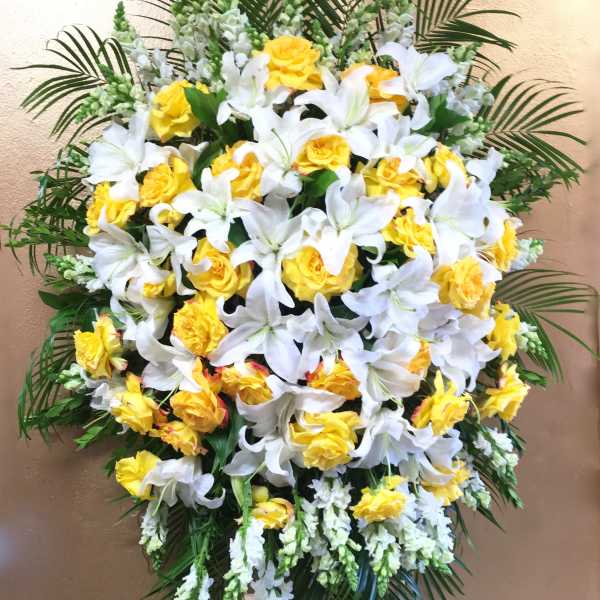 Standing floral spray with white lilies and yellow roses on an easel
