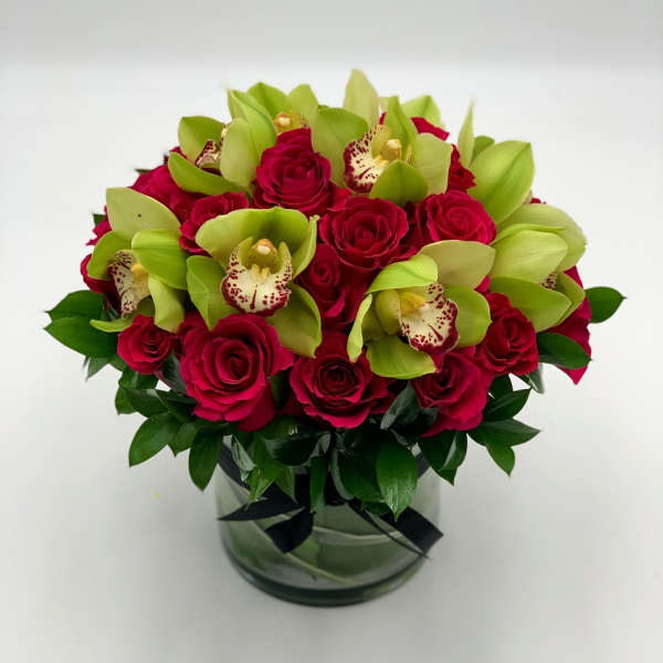Bouquet of red roses and green orchids in a glass vase