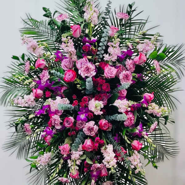 Large standing spray of pink and purple flowers with palm fronds