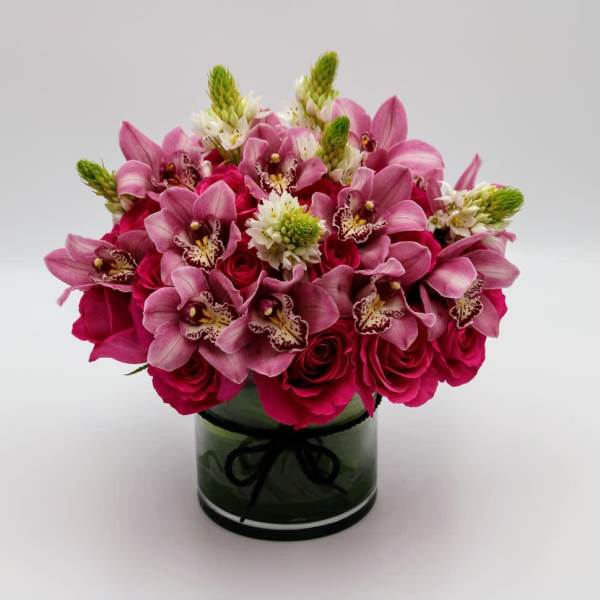 Pink orchids and roses arranged in a glass vase