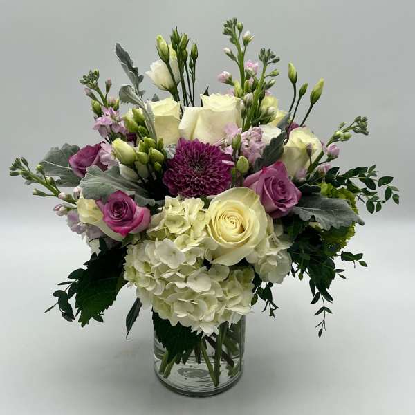 Bouquet of cream and purple flowers in a clear glass vase