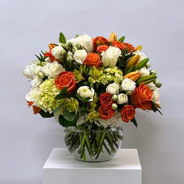 Bouquet of orange and white roses in a clear glass vase