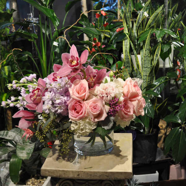 Pink roses and orchids arranged in a clear glass vase