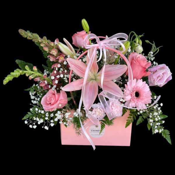Pink floral arrangement in a pink box with ribbon