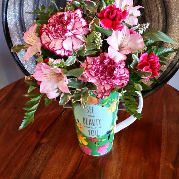 Pink and white flower arrangement in a decorative mug