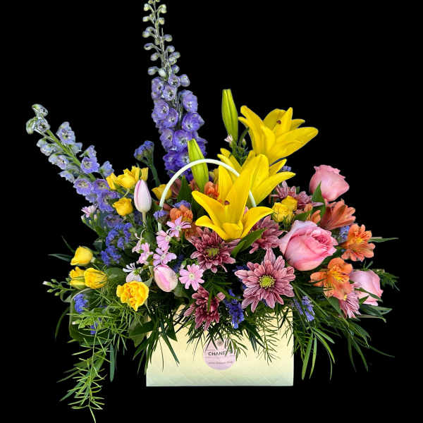 Mixed bouquet with yellow lilies, pink roses, and purple flowers in a white box