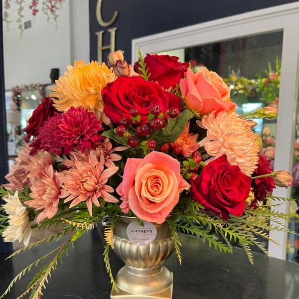 Bouquet of red and peach roses with pink chrysanthemums in a gold vase