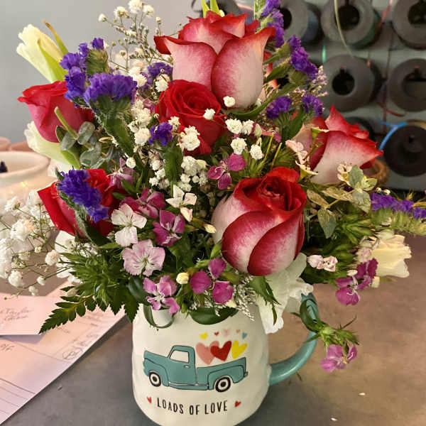 Bouquet of red and white roses in a mug with a truck design