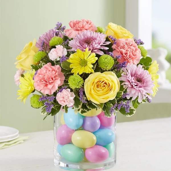 Pastel bouquet in a clear vase filled with colorful eggs
