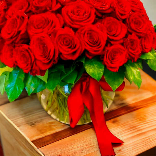 Bouquet of red roses in a glass vase with a red ribbon