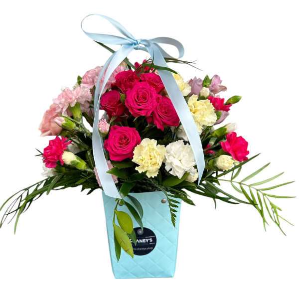Pink and white roses with carnations in a blue gift bag