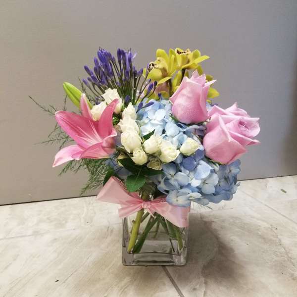 Mixed bouquet of pink lilies, roses, hydrangea, and orchids in a glass vase