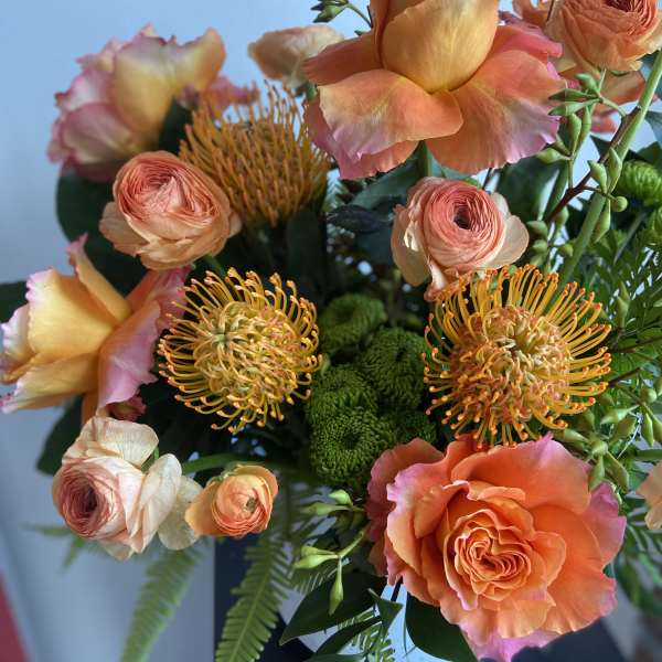 Orange and peach bouquet with roses and pincushion blooms