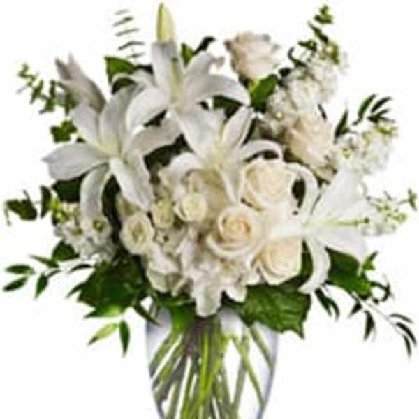 White lilies and roses arranged in a clear glass vase