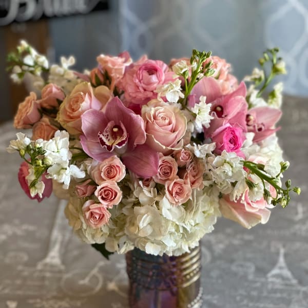 Pink roses and orchids arranged in a glass vase