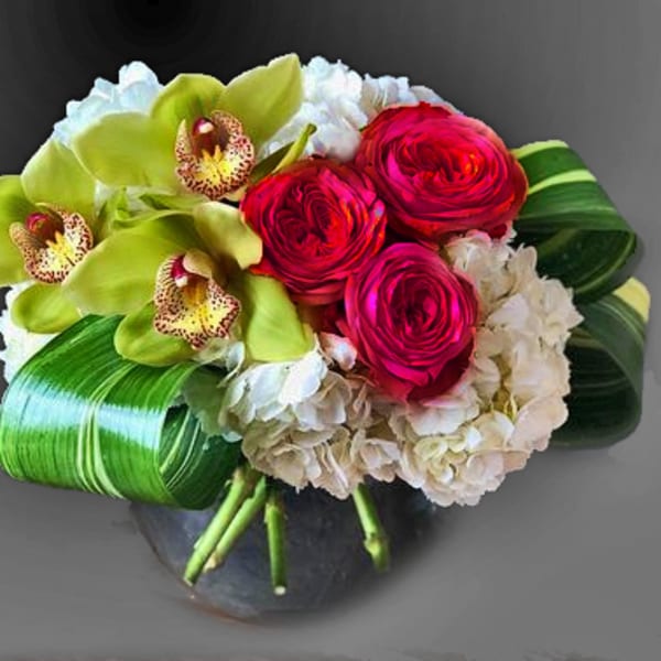 Bouquet of red roses, green orchids, and white hydrangeas in a vase