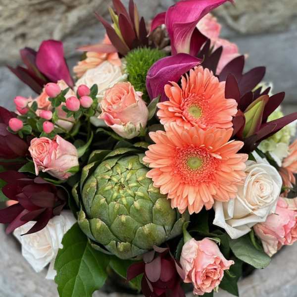Bouquet with peach roses, coral gerbera daisies, and a green artichoke centerpiece