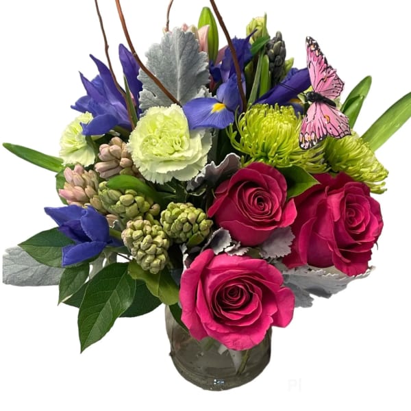 Mixed bouquet in a glass vase with roses, irises, and a butterfly accent