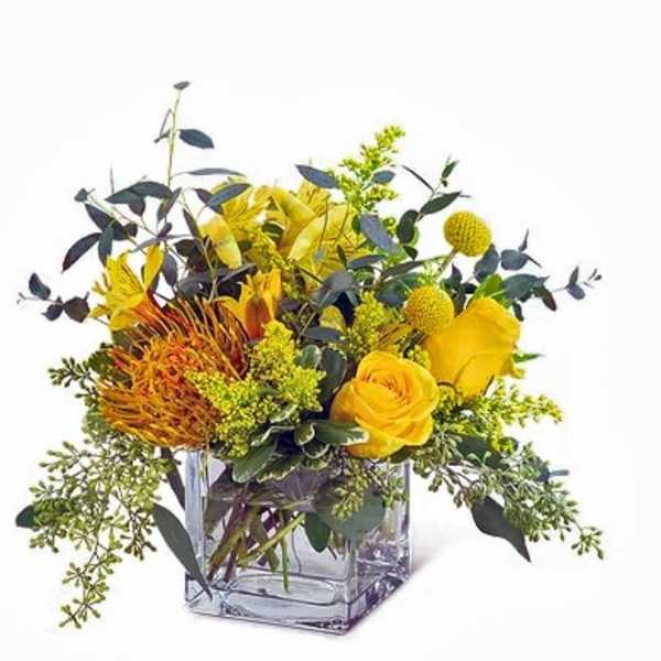 Yellow floral arrangement in a clear square glass vase
