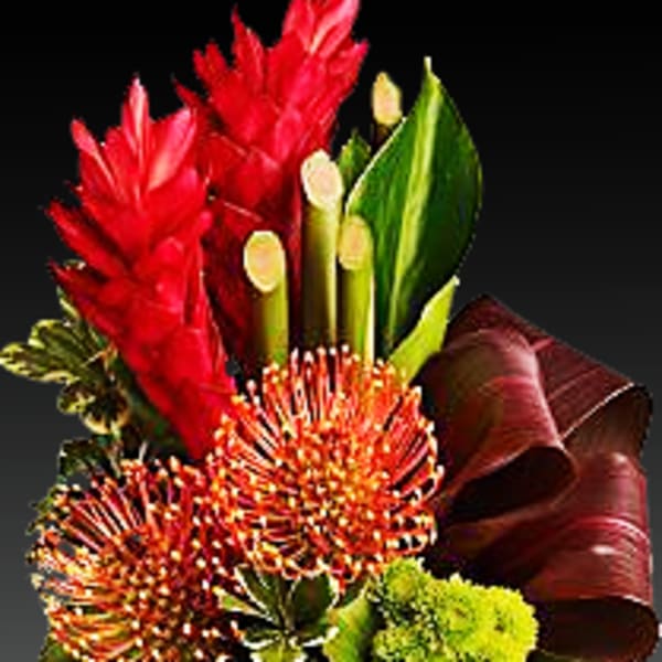 Tropical bouquet with red blooms and green leaves in a copper vase