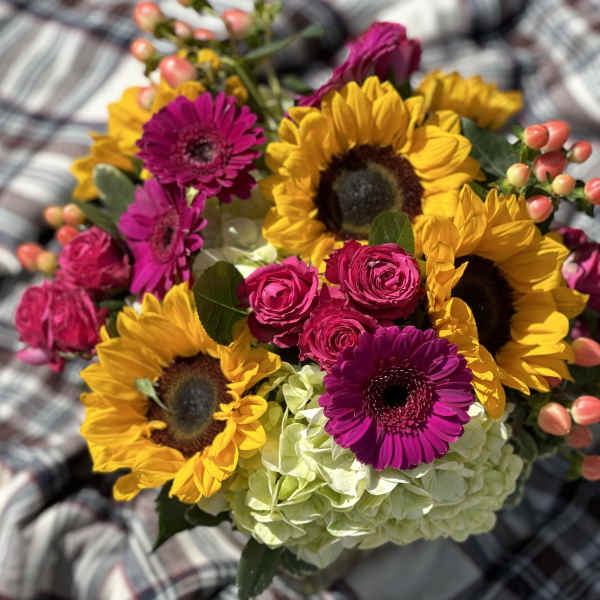 Bouquet of sunflowers, pink gerbera daisies, roses, and pale hydrangea
