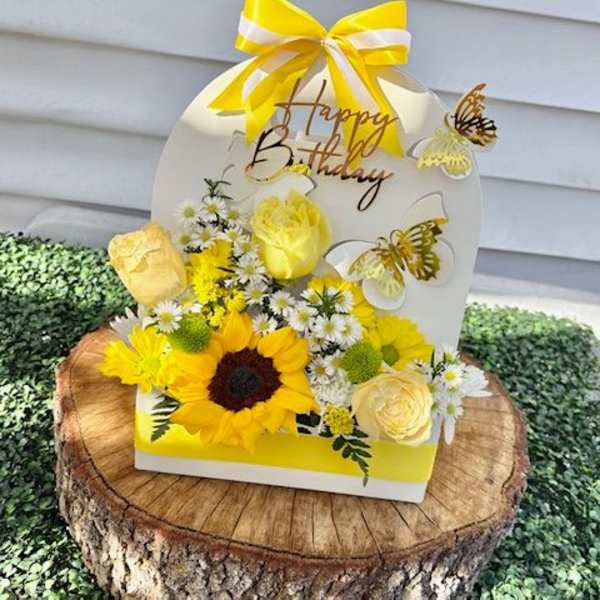 Yellow floral birthday arrangement with a ribbon and butterfly accents