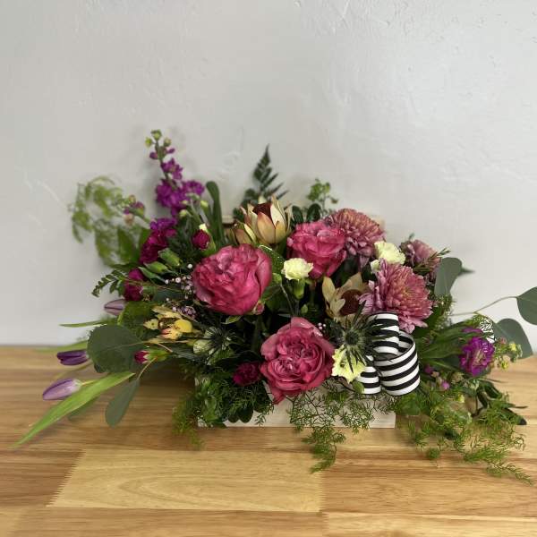 Pink and purple floral arrangement in a low rectangular container