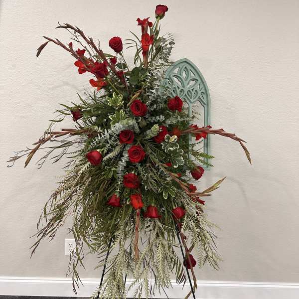 Tall red rose arrangement on a stand with cascading greenery