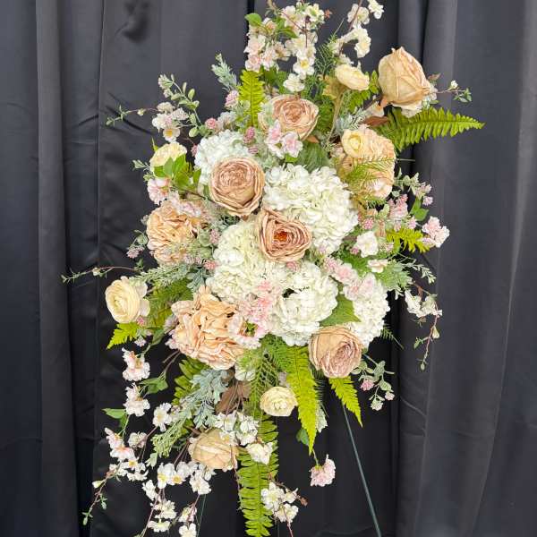 Tall floral spray with cream and blush roses, white hydrangeas, and trailing blossoms