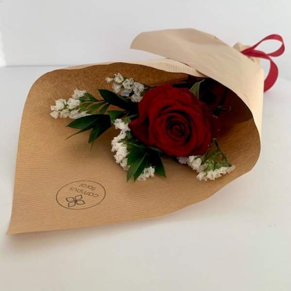 Single red rose wrapped in brown paper with white filler flowers