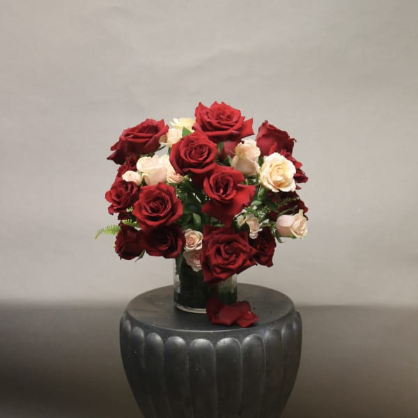 Red and blush roses arranged in a clear glass vase