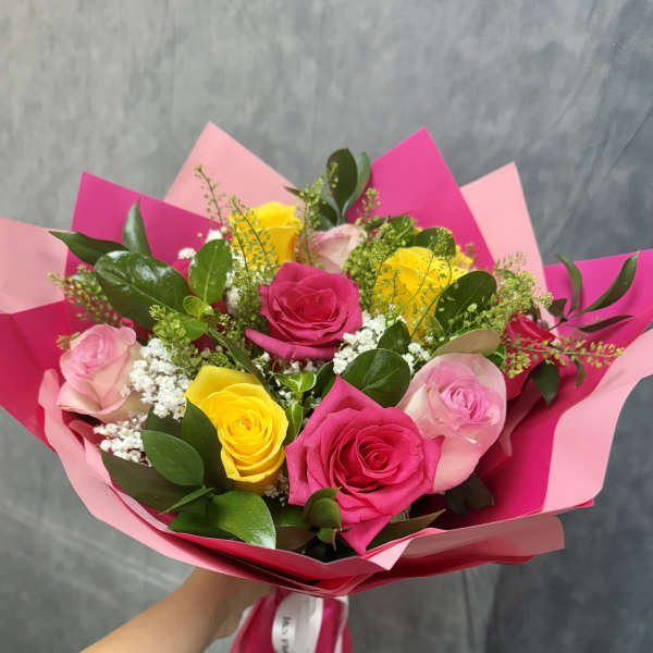 Bouquet of pink and yellow roses wrapped in bright pink paper