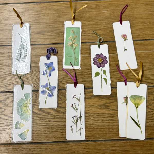 Pressed flower bookmarks tied with ribbons on a wooden surface