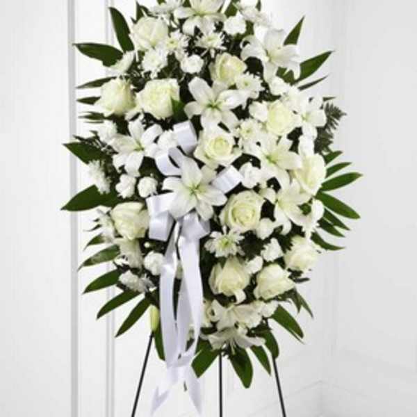 White funeral spray with roses and lilies on a stand