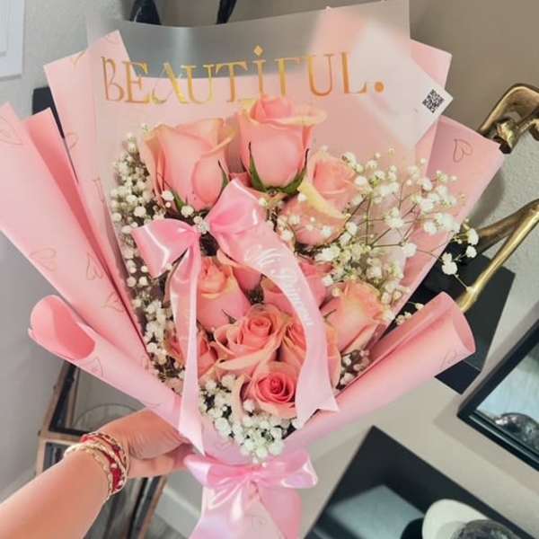 Pink rose bouquet wrapped in pastel paper with a ribbon