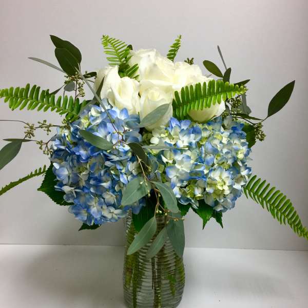 Blue hydrangeas and white roses in a glass vase