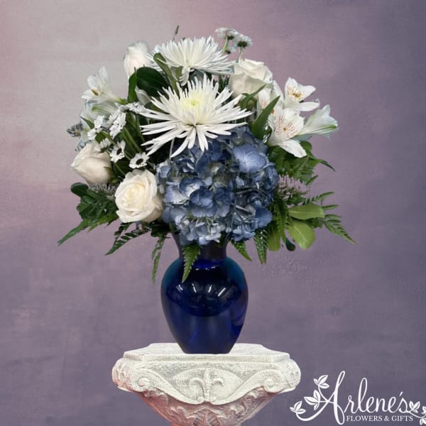 White and blue floral arrangement in a cobalt vase