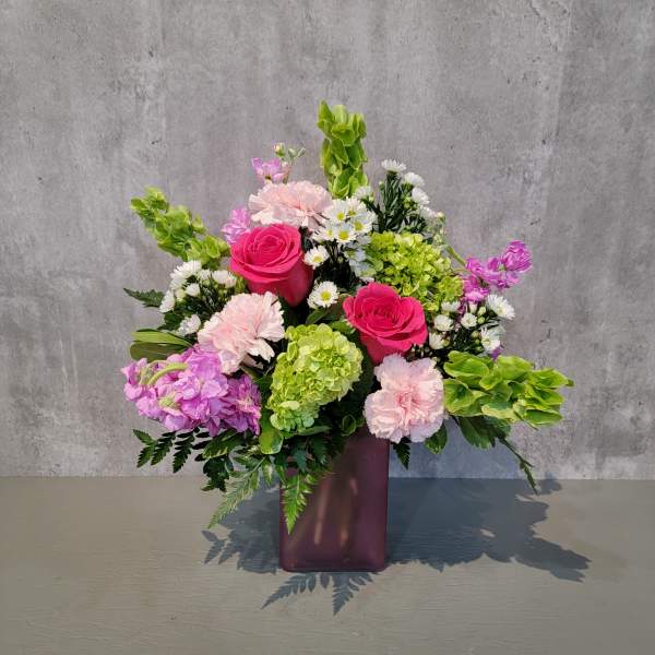 Pink roses and hydrangeas in a purple vase with white daisies