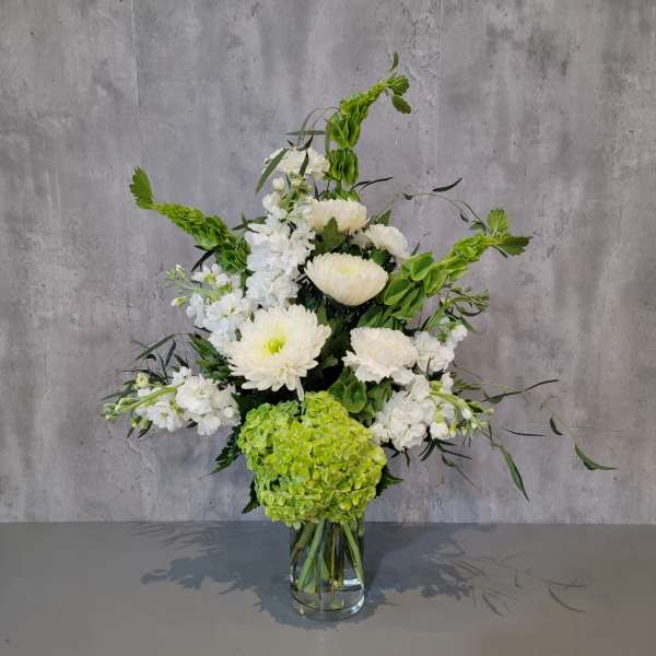 White flowers and green hydrangea in a clear glass vase