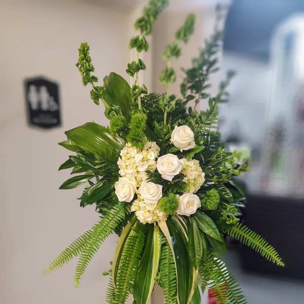 White roses and hydrangeas in a tall green standing arrangement