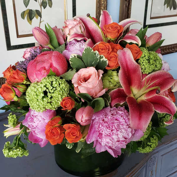 Pink lilies and roses arranged in a dark vase