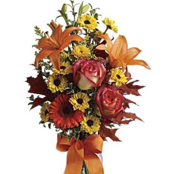 Orange lilies and roses with yellow daisies in a glass vase