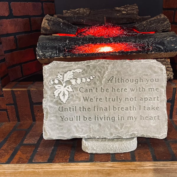 Decorative memorial plaque with an engraved poem in front of faux glowing logs