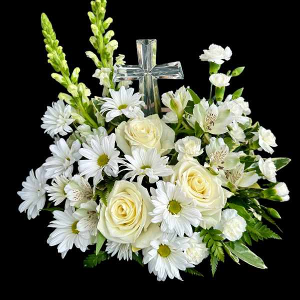 White floral arrangement with roses, daisies, and a clear glass cross