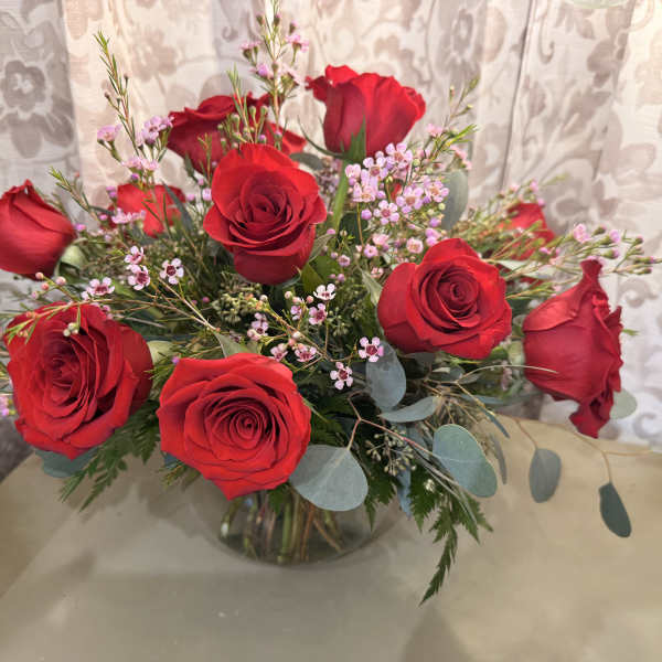 Bouquet of red roses with pink filler flowers in a glass vase